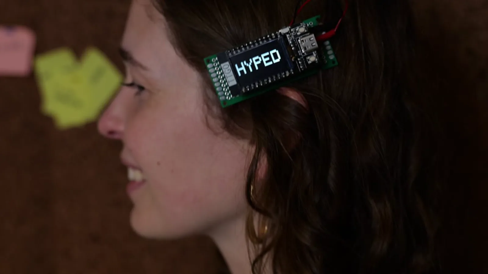 The finished digital hair clip, worn, showing the word HYPED on its screen.