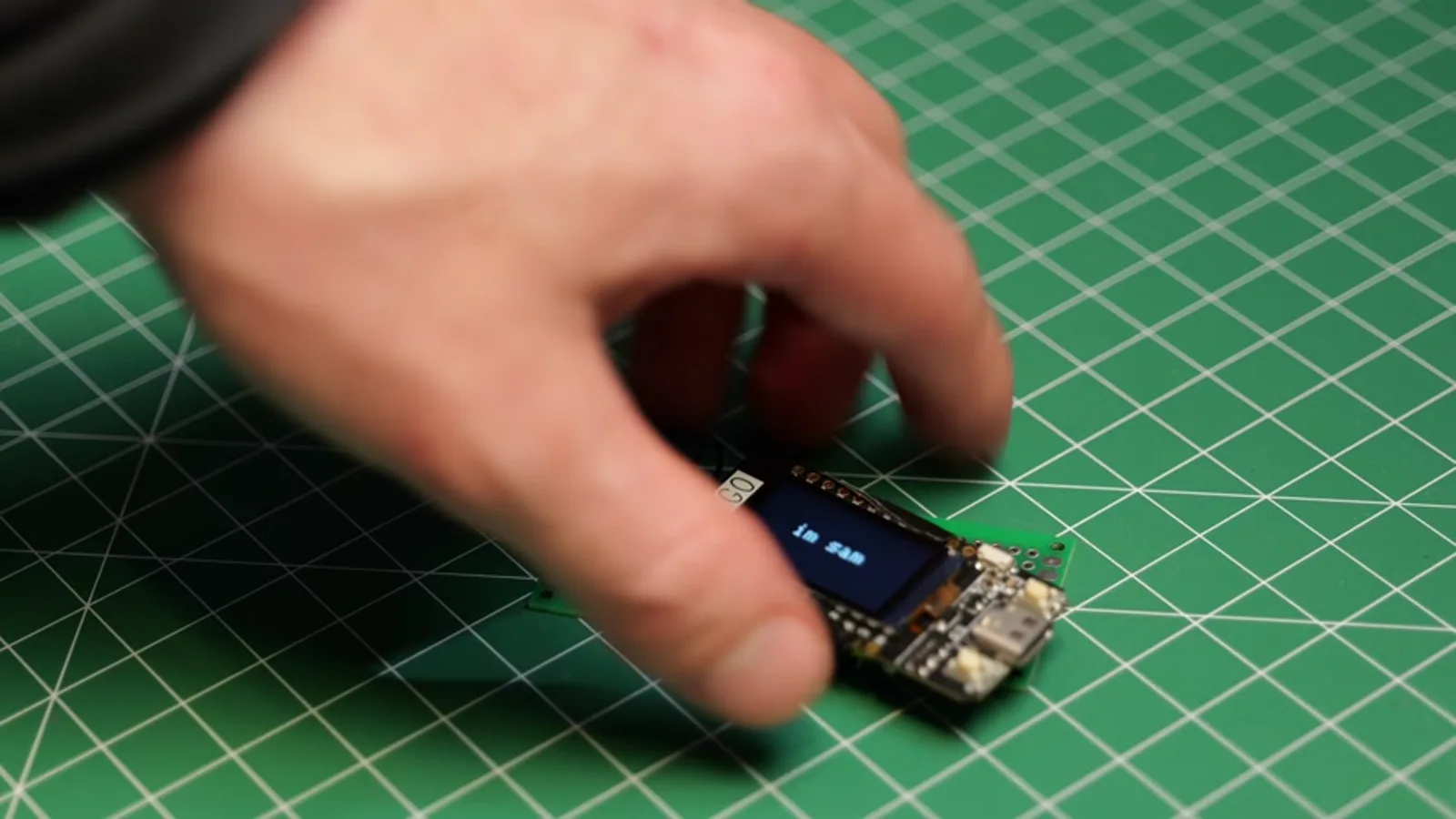 The LilyGo T-Display running the starter code on the workbench, screen lit.