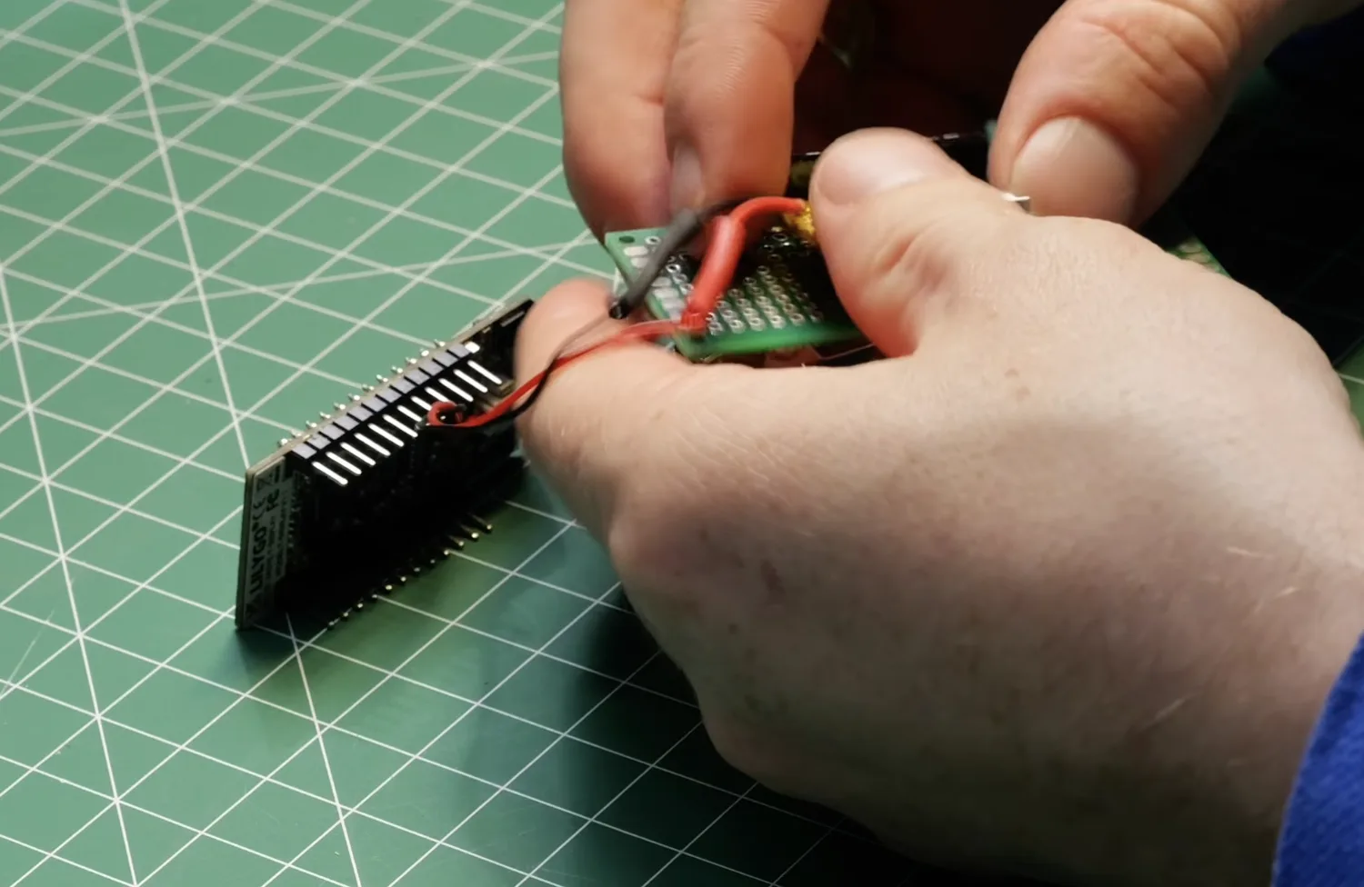 Threading the red battery wire through the proto board, with the pinned T-Display alongside.