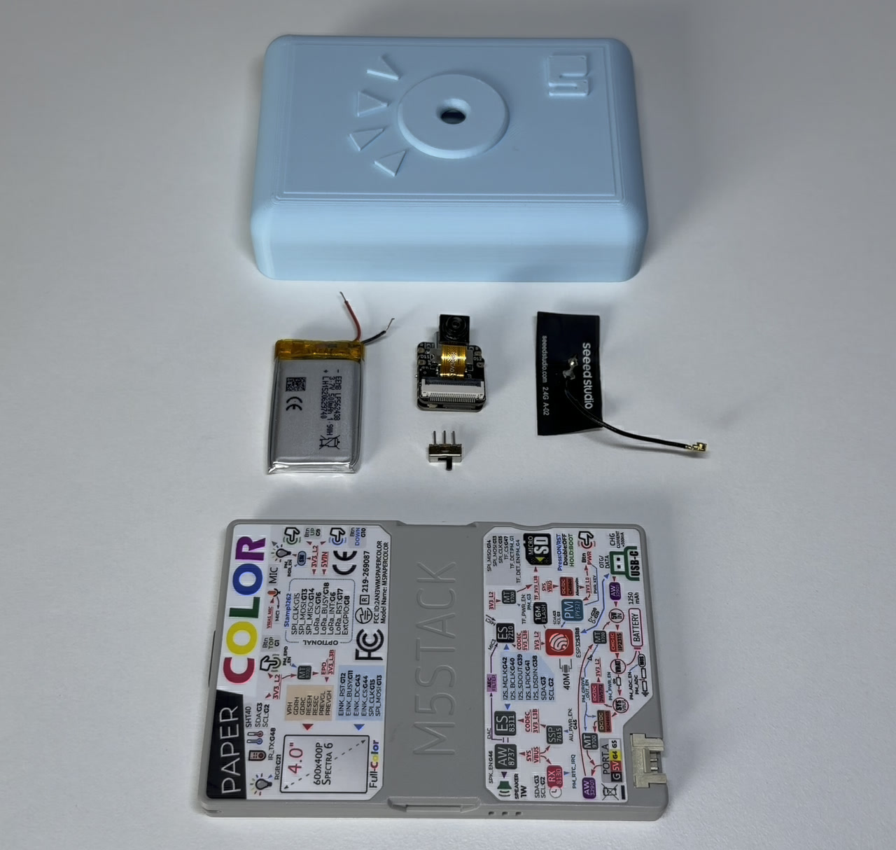 Everything that goes into the build, laid out: shell, LiPo, XIAO with the OV3660, the toggle switch, the antenna, and the PaperColor.