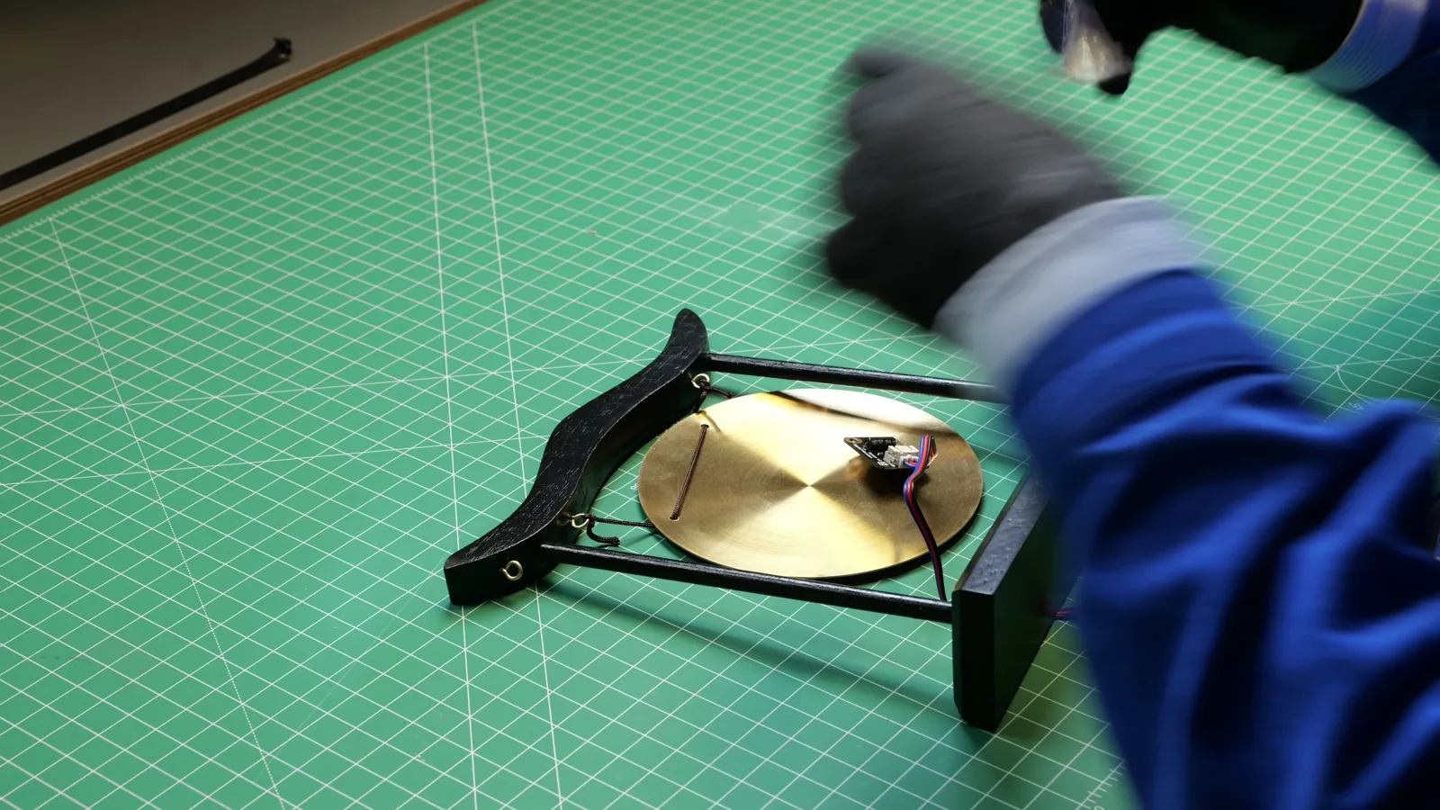 Gluing the sensor to the back of the gong, with gloves on.